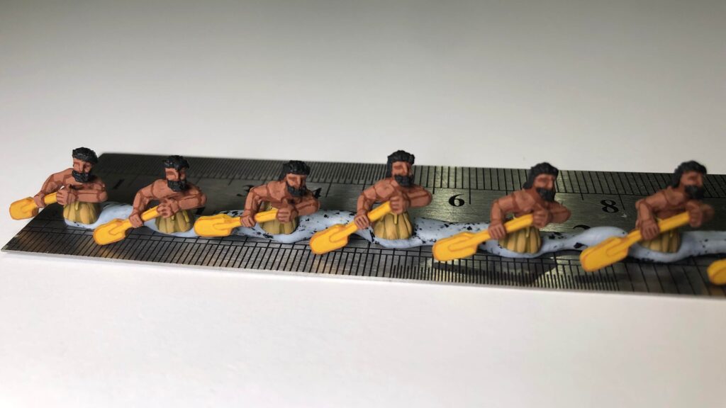 Small-scale miniatures on a metal ruler, illustrating how facial features are simplified at 10mm and below.