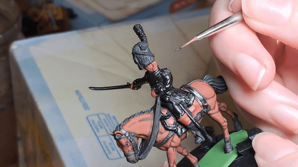 Close-up of the initial brown flesh basecoat on a 28mm miniature soldier's face before applying shading.