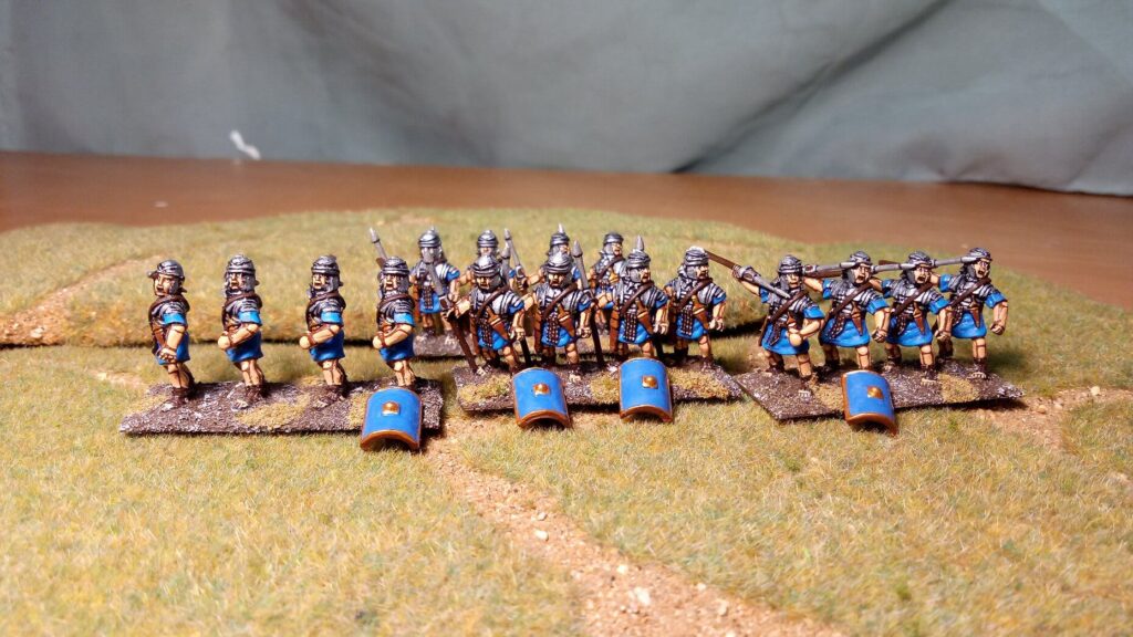 Painted historical wargaming miniatures with simple grass and sand basing standing on a green gaming mat with a path.