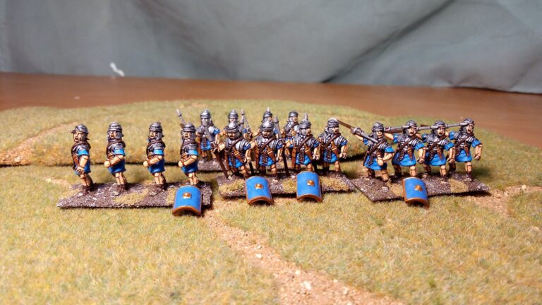 Painted historical wargaming miniatures with simple grass and sand basing standing on a green gaming mat with a path