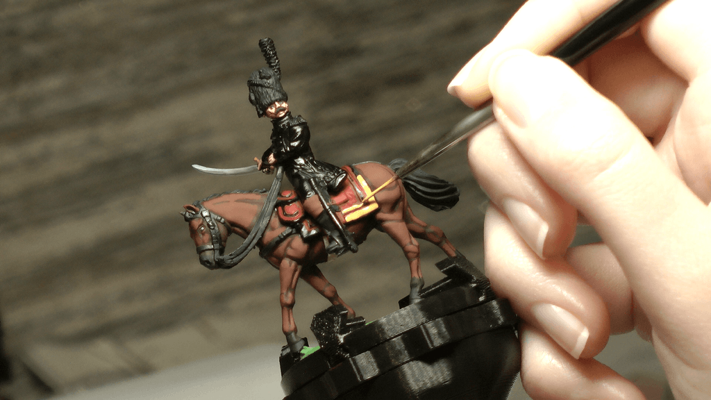 Painter adding fine details by hand to a cavalry miniature